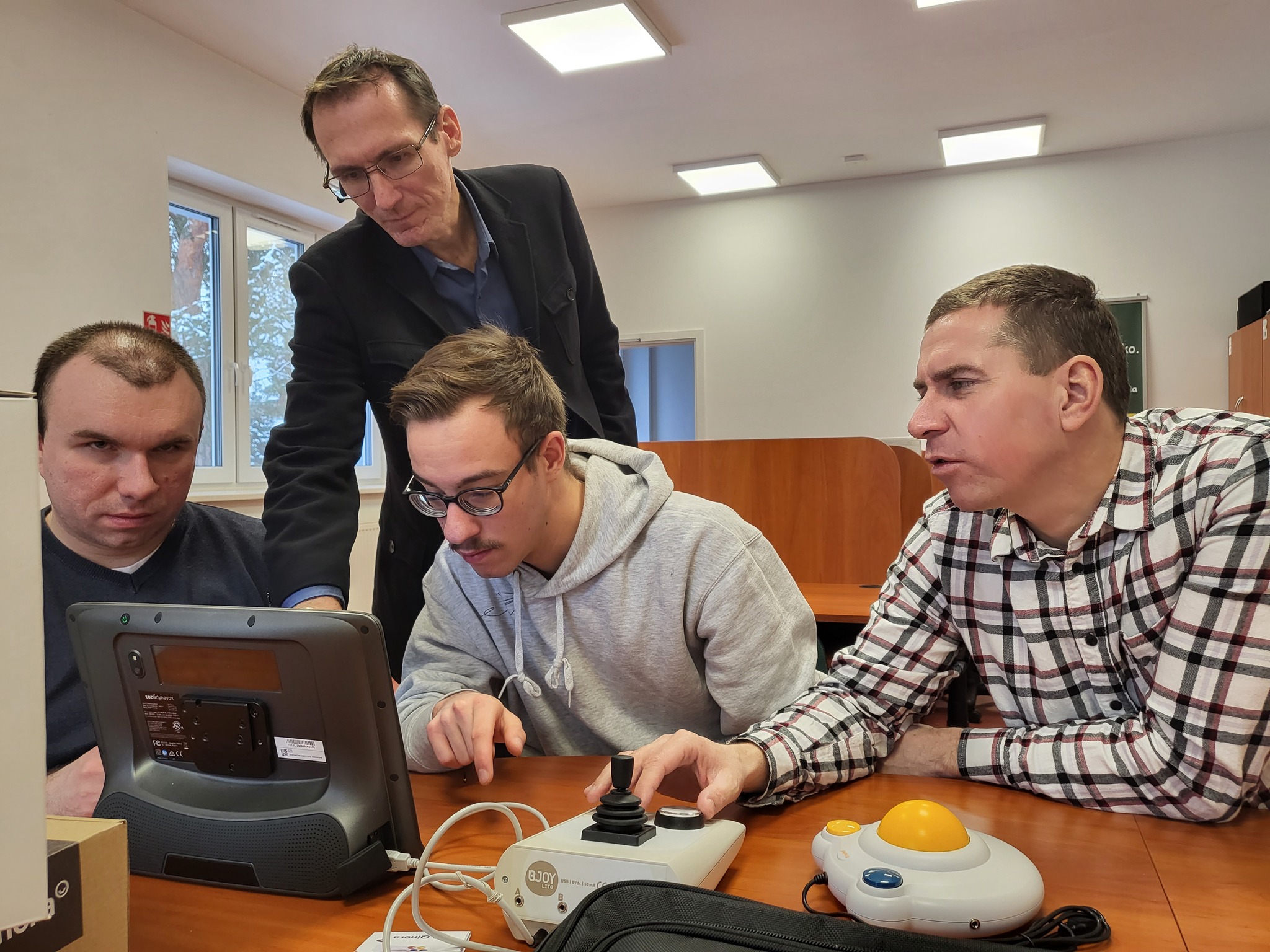 Zebrani przy biurku goście oglądają sprzęt.