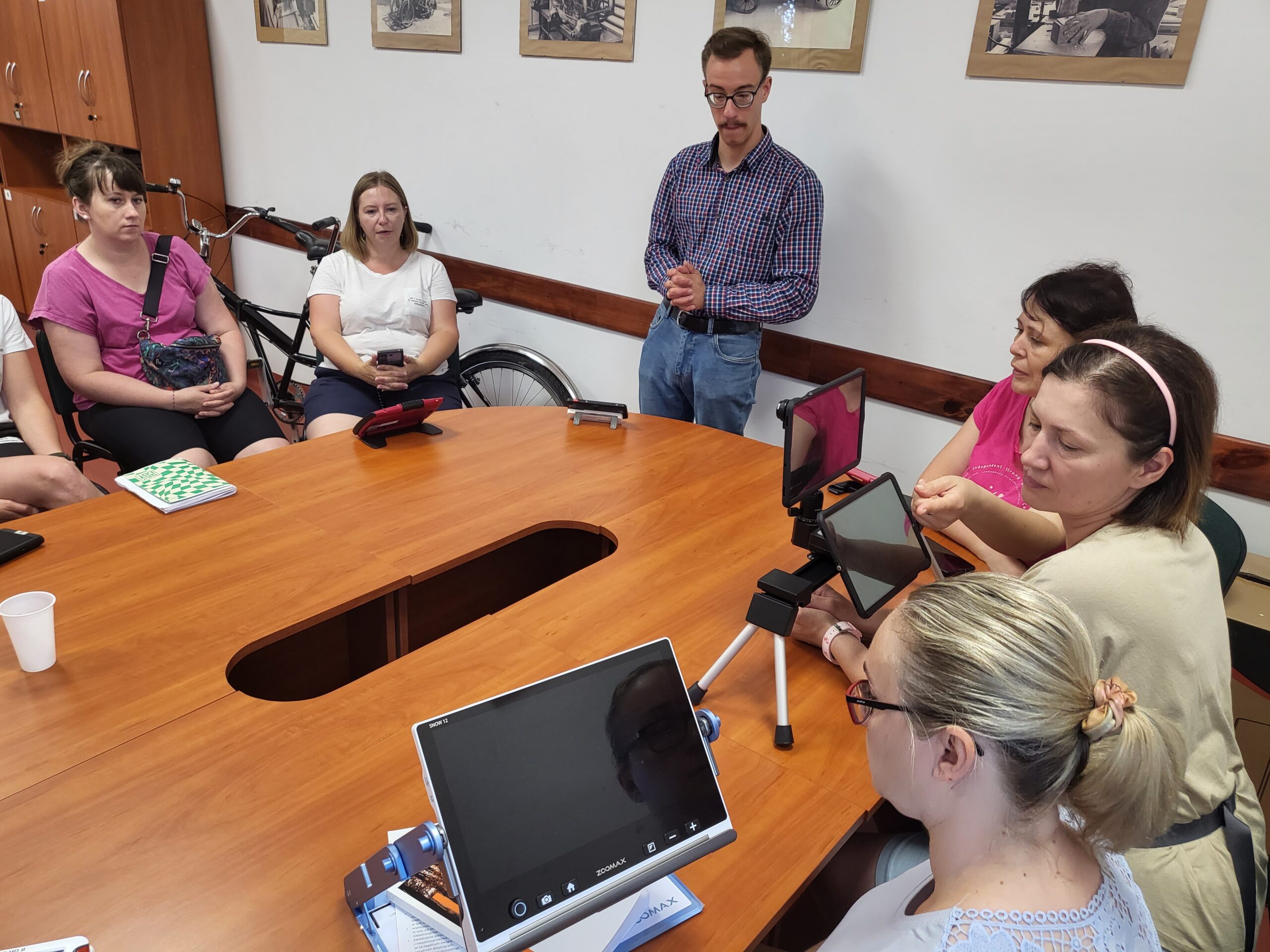 Uczestnicy oglądają różne sprzęty przy stole.