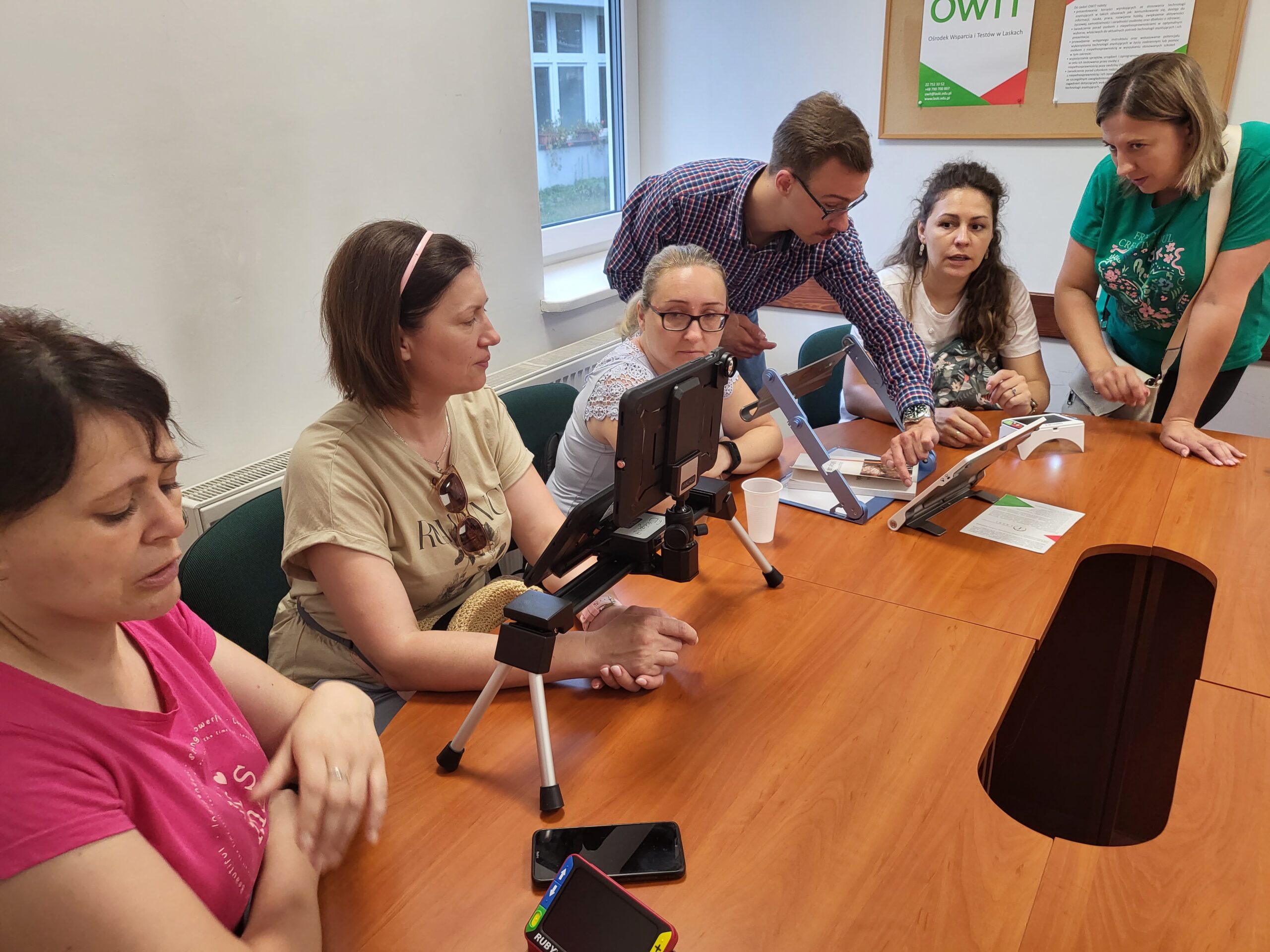 Uczestnicy oglądają różne sprzęty przy stole.