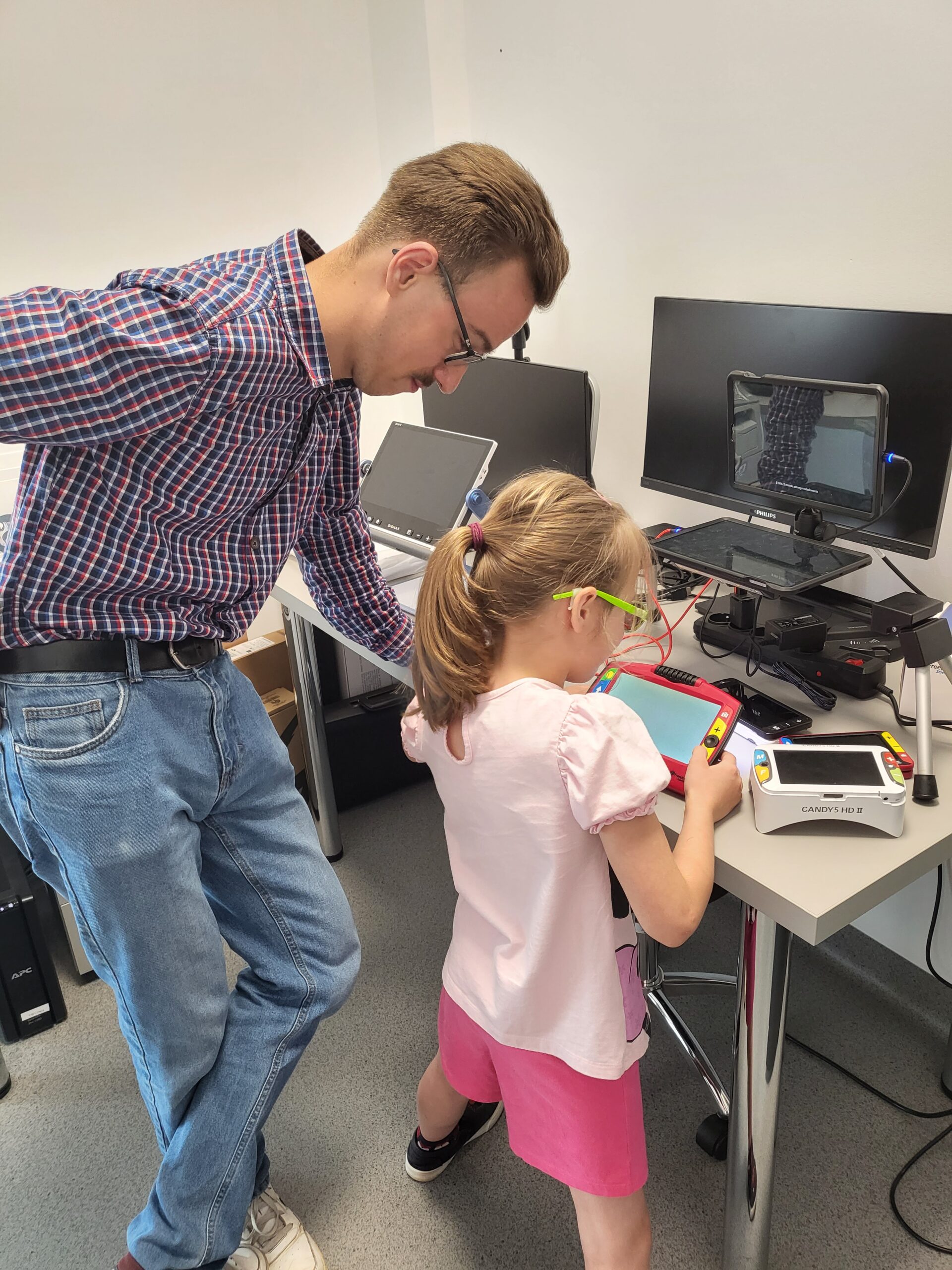 Pracownik prezentuje dziecku sprzęt komputerowy.