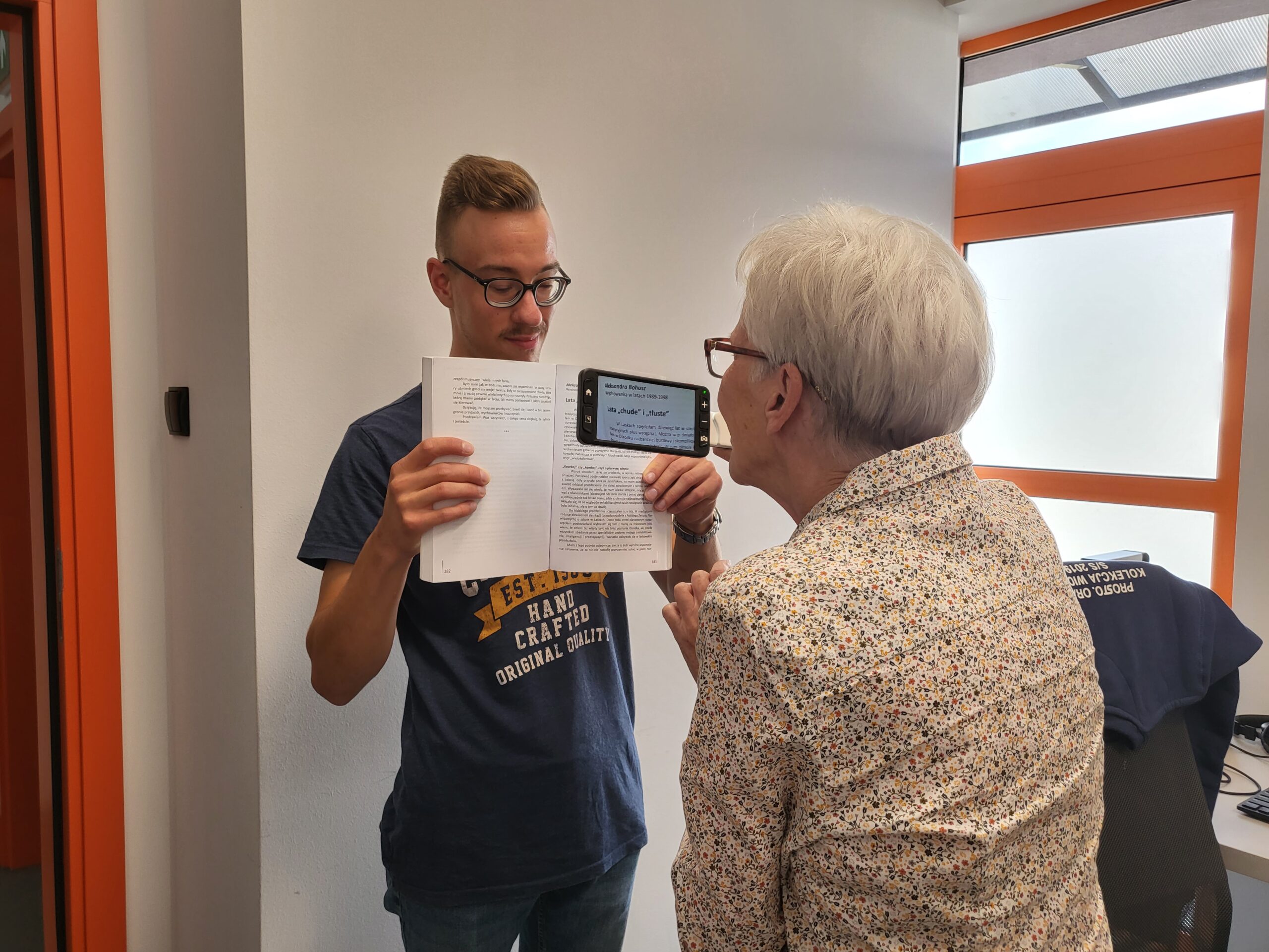 Starsza kobieta czyta tekst z lupą.