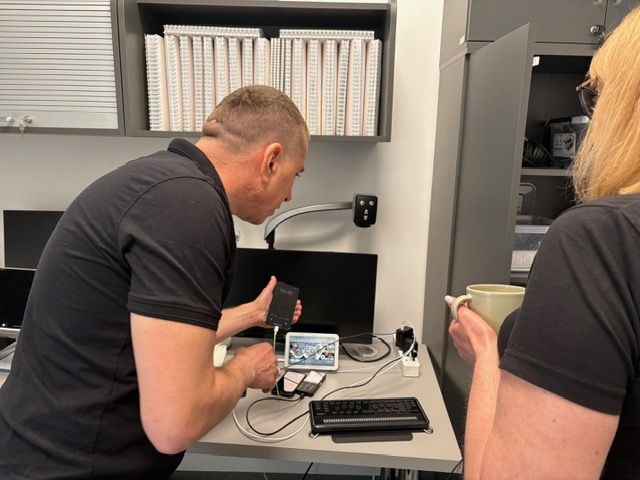 Pracownicy prezentują urządzenia elektroniczne.