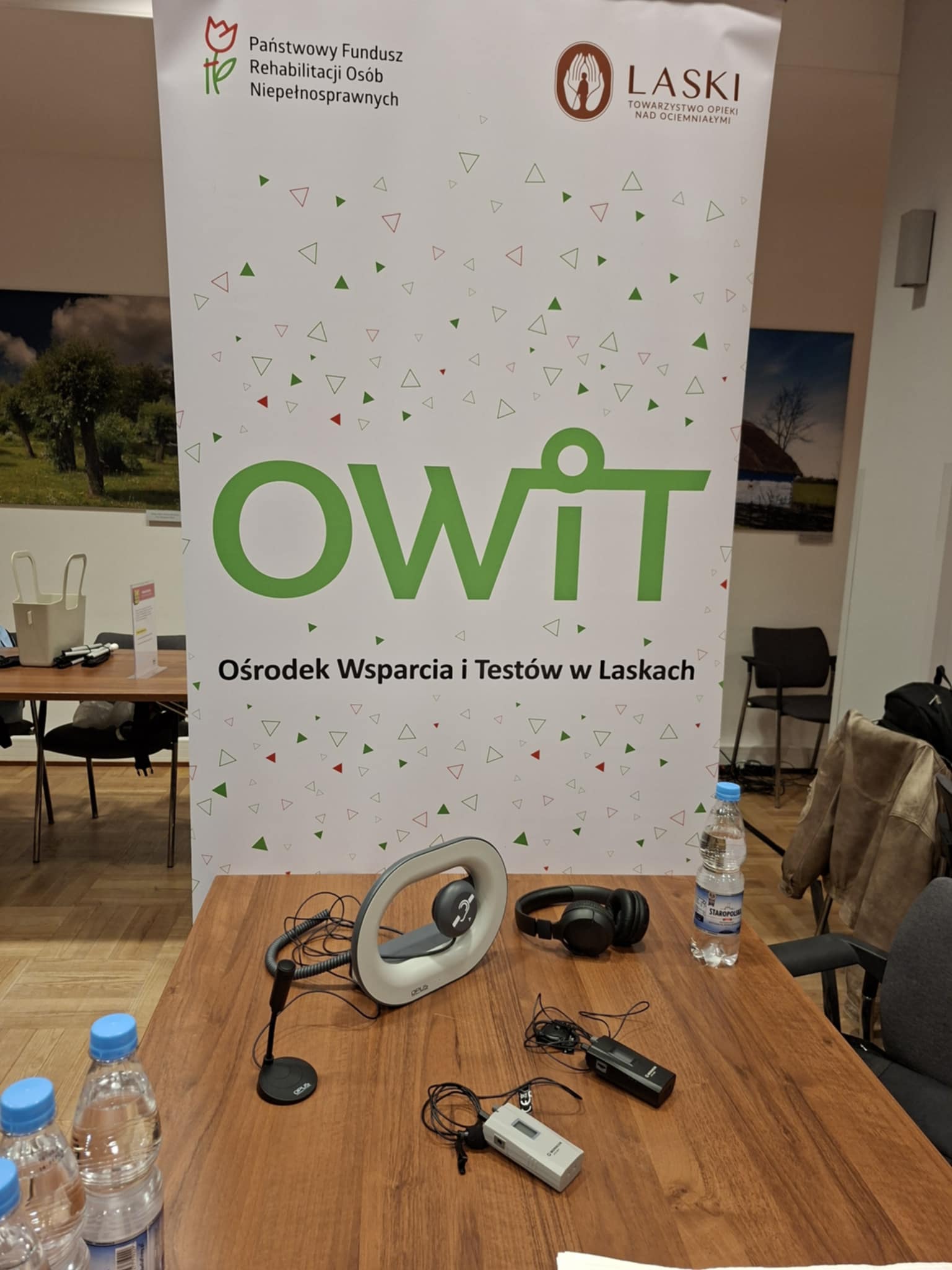 Sprzęt leżący na biurku, obok rollup OWiT.