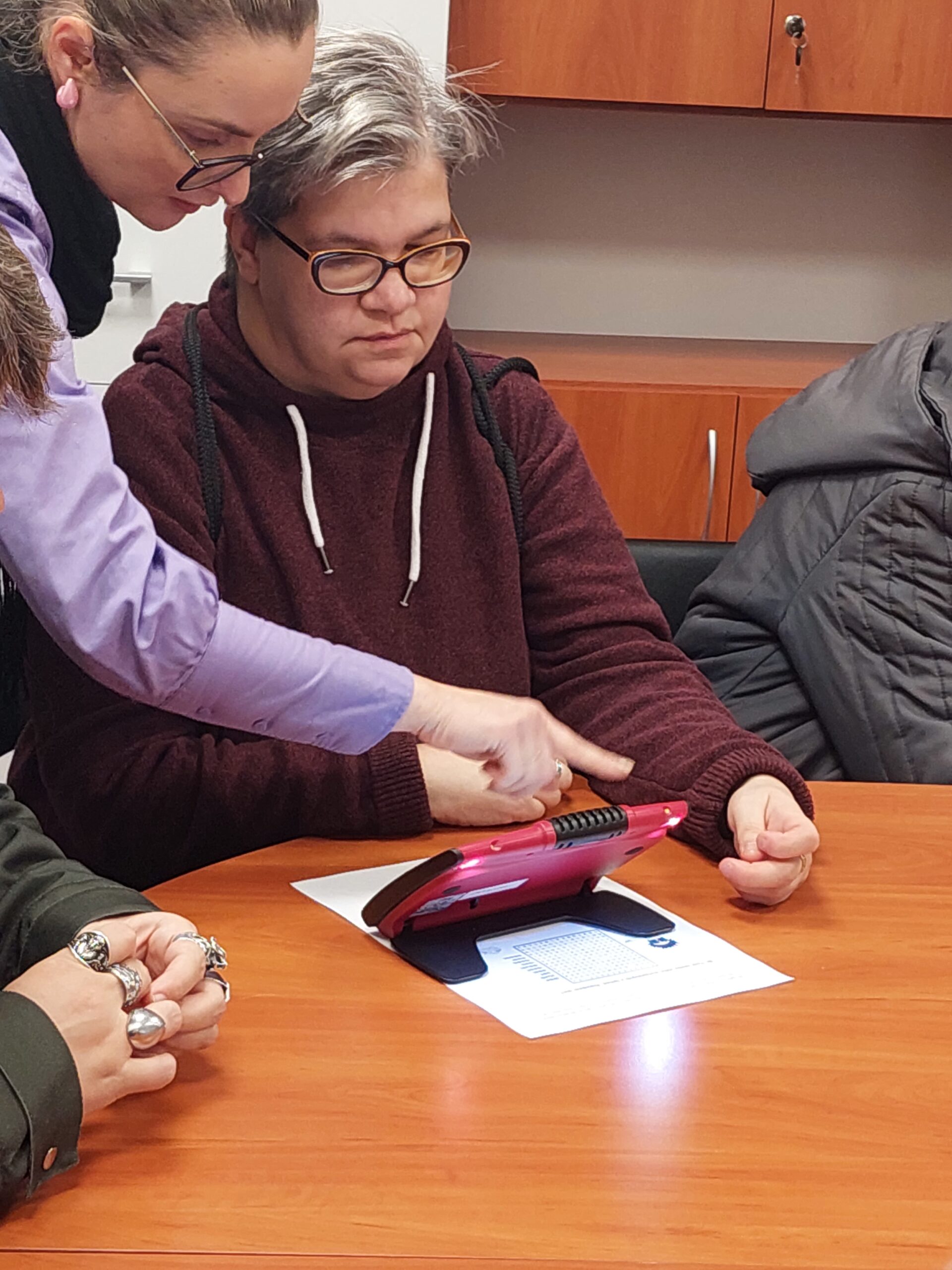 Uczestniczka ogląda lupę przy pomocy pracownika OWiT